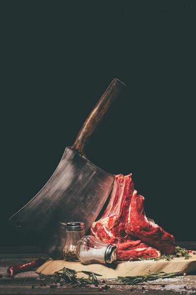 raw pork ribs on cutting board with spices and butcher cleaver