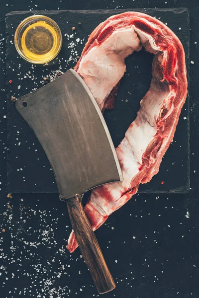 Top view of raw ribs slice with cleaver and oil on stone slate — Stock Image Top View Raw Ribs Slice Cleaver Oil Stone Slate Stock Picture
