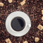 Top view of cup of coffee, brown sugar, coffee beans on sack clothes