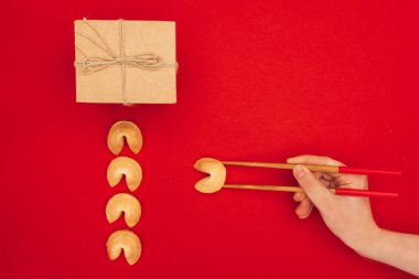 cropped shot of woman taking chinese fortune cookie with chopsticks, Chinese New Year concept clipart