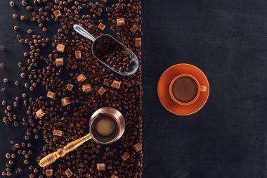 kahve fincan tabağı, kavrulmuş kahve çekirdekleri, kahverengi şeker, cezve ve kepçe ile üstten görünüm siyah