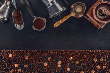 top view of roasted coffee beans with brown sugar and various coffee makers and grinders on black clipart