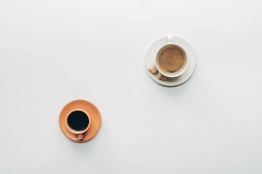 iki bardak kahve saucers ve üzerinde beyaz izole kahverengi şeker ile Üstten Görünüm 
