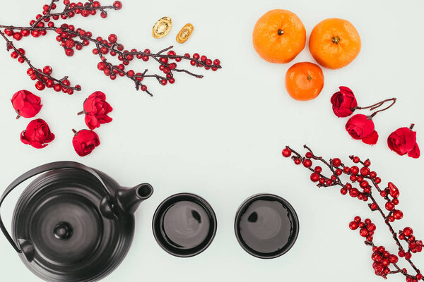 top view of chinese new year composition with tea and branches of berries isolated on white