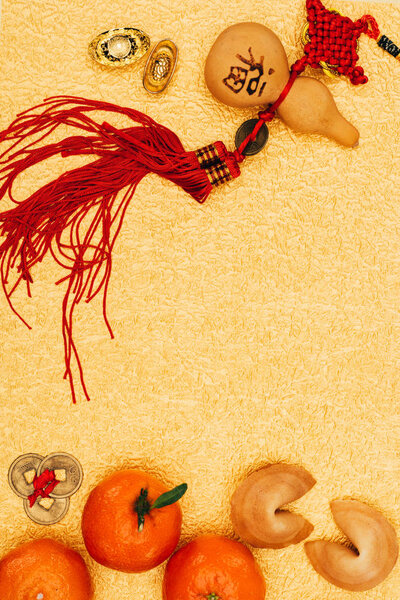 top view of traditional chinese talisman with tangerines and fortune cookies on golden surface, Chinese New Year concept