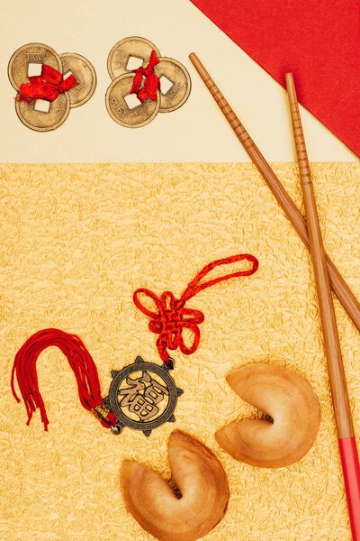 top view of chinese talismans with fortune cookies and chopsticks on golden surface, Chinese New Year concept