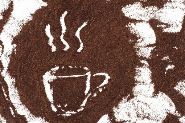 top view of cup of coffee sign drawn in coffee on white