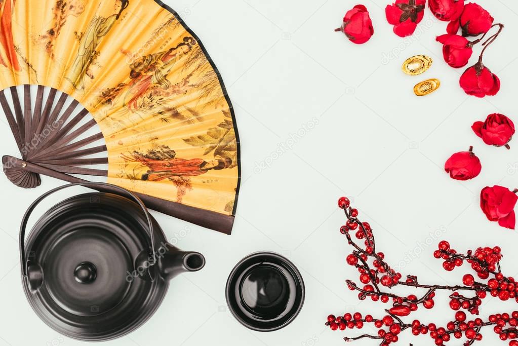 top view of chinese new year composition with tea and handheld fan isolated on white