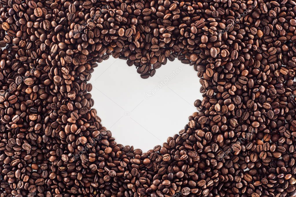 top view of heart made from roasted coffee beans on white 