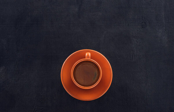 top view of cup of coffee with saucer on black
