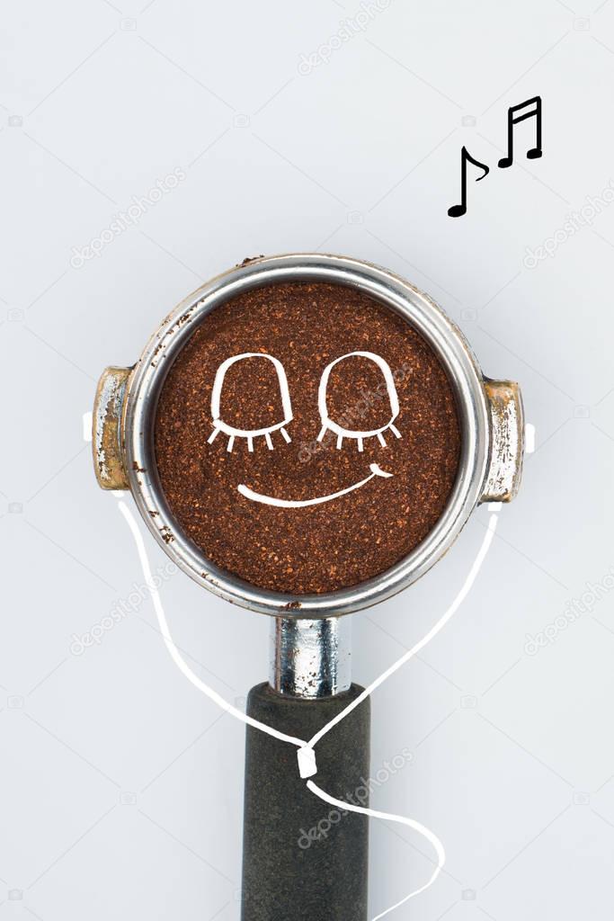 top view of coffee tamper with smiley face and earphones isolated on white