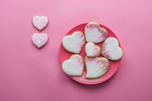 top view of sweet glazed cookies on plate isolated on pink, st valentines day holiday concept