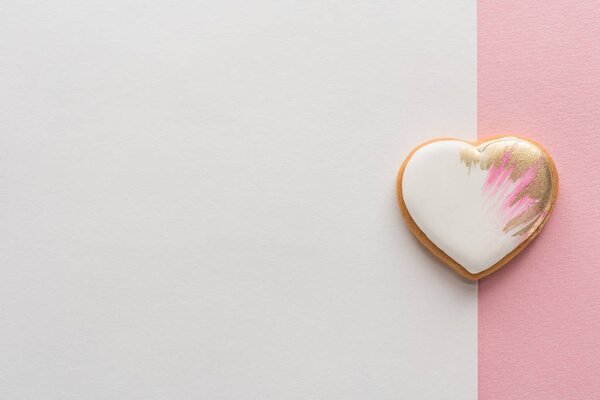 top view of glazed heart shaped cookie on pink surface