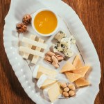 Top view of cheese plate with nuts and sauce on wooden table