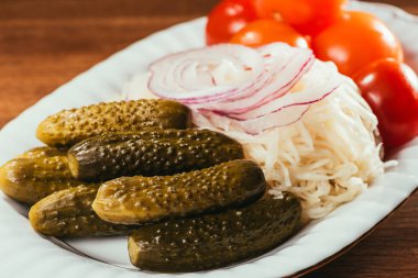 Close-up view of sauerkraut served with pickled vegetables on white plate clipart
