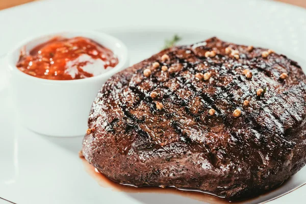 白いプレートに胡椒とソースのグリル ステーキのクローズ アップ ビュー — ストック写真