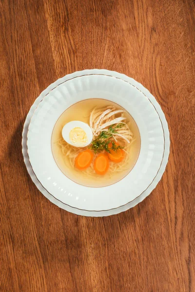 Top view of chicken soup with vegetables and egg in white plate on wooden table — Stock Image Top View Chicken Soup Vegetables Egg White Plate Wooden Table Royalty Free Stock Images