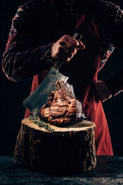 cropped shot of chef in apron holding meat knife and delicious grilled ribs on wooden stump  clipart