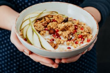 kadın aşçı granola meyve ve fındık ile bir kase tutarak kırpılmış görüntü
