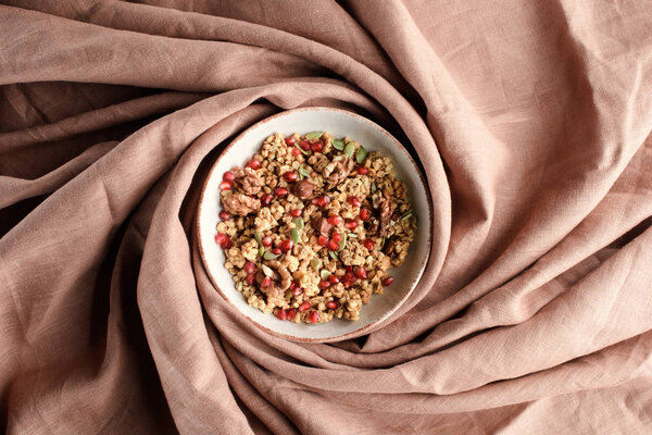 вид сверху на плиту с домашней гранолой на бежевой скатерти
