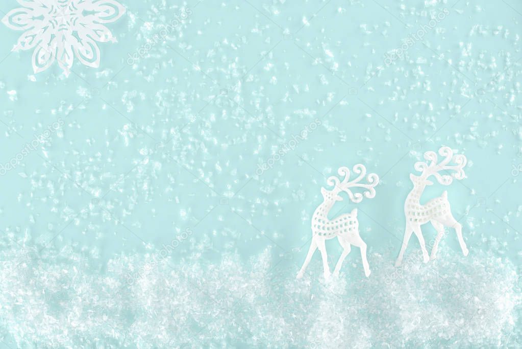 christmas background with decorative snow, snowflake and paper deer, isolated on light blue