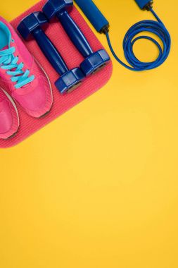 Spor malzemeleri ile ayakkabı, halter ve atlama ipi sarı izole