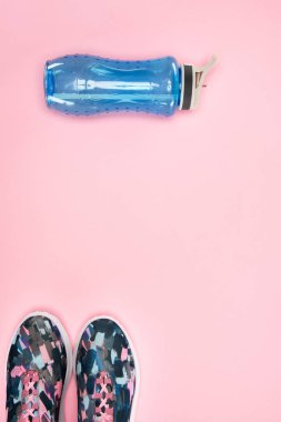 Spor ayakkabı ve su şişesi üzerinde pembe izole