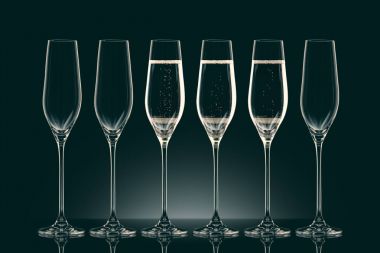 three transparent glasses with champagne and three empty glasses on black clipart