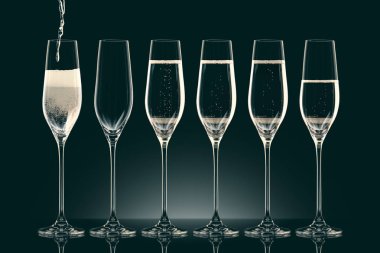 pouring champagne into six transparent glasses on black clipart