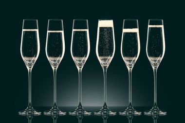 six transparent glasses with champagne on black clipart