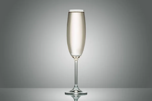 一个透明的玻璃与平静的香槟在灰色 — 图库照片