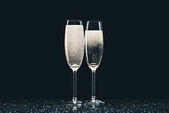 zwei Gläser Champagner mit Tropfen auf dem Tisch auf schwarz