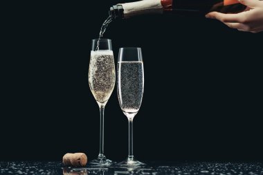 cropped image of woman pouring champagne from bottle into glasses on black clipart