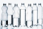 Kunststoffflaschen mit Wasser in Reihe isoliert auf weiß