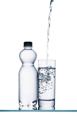 still life with plastic bottle and water pouring into glass isolated on white clipart