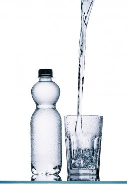 plastic bottle and water pouring into glass isolated on white clipart