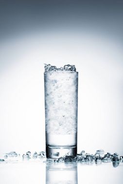 glass of cold water with crushed ice on reflective surface on white  clipart