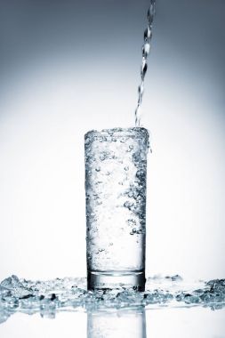 cold water pouring into glass on white  clipart