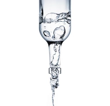 yakın çekim shot cam şişe üzerinde beyaz izole dökülen su
