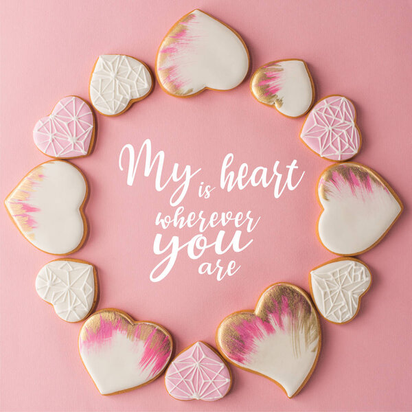 flat lay with arrangement of glazed heart shaped cookies isolated on pink surface
