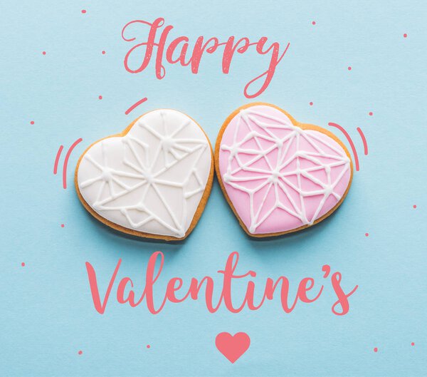 top view of two glazed heart shaped cookies isolated on blue, st valentines day holiday concept