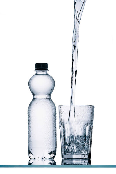 пластиковая бутылка и вода наливая в стекло изолированы на белом
