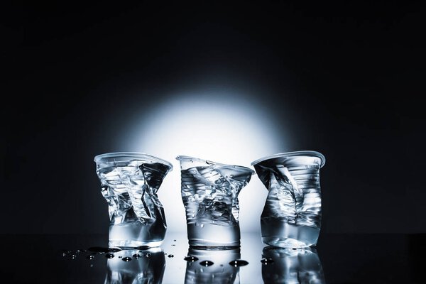 crumpled plastic cups of water on dark 