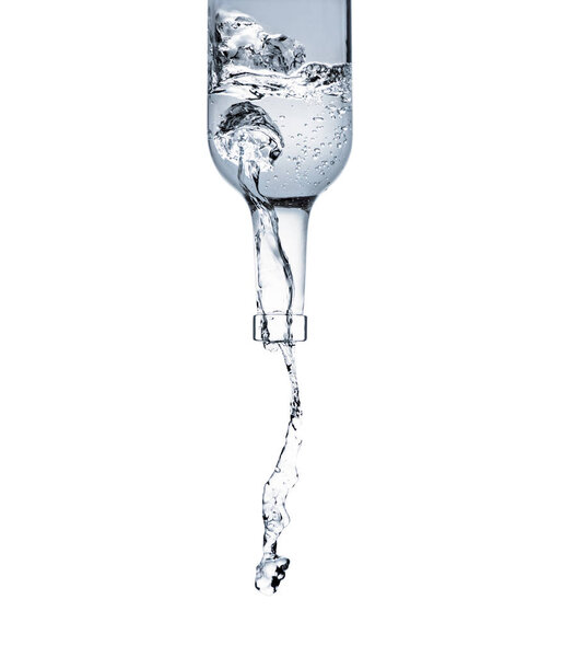 motion shot of water pouring from glass bottle isolated on white