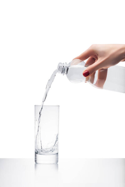 обрезанный снимок женщины, наливающей воду в стекло из пластиковой бутылки, изолированной на белом
