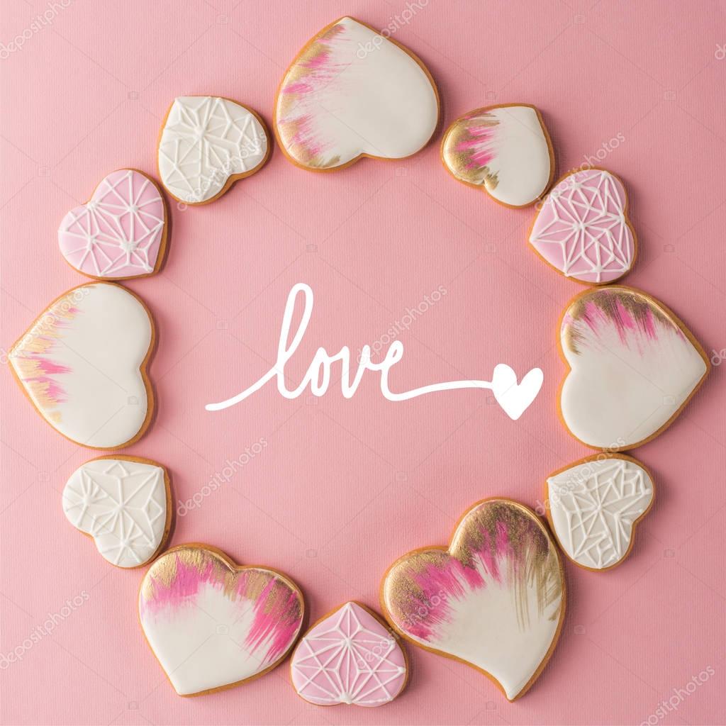 Flat lay with arrangement of glazed heart shaped cookies isolated on pink surface