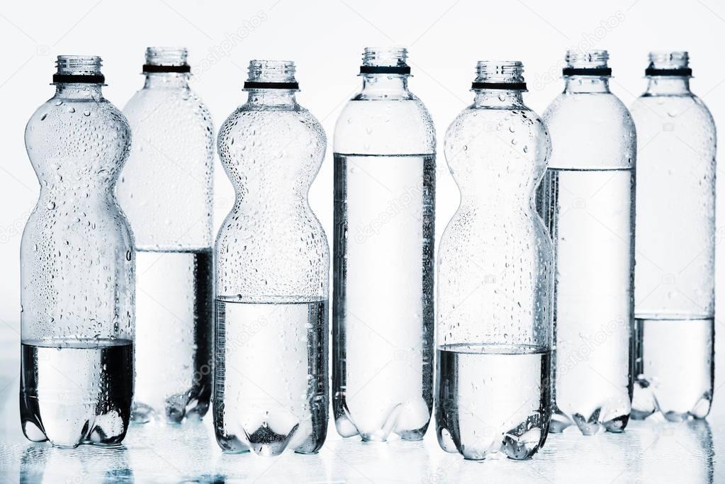 plastic bottles of water in row isolated on white