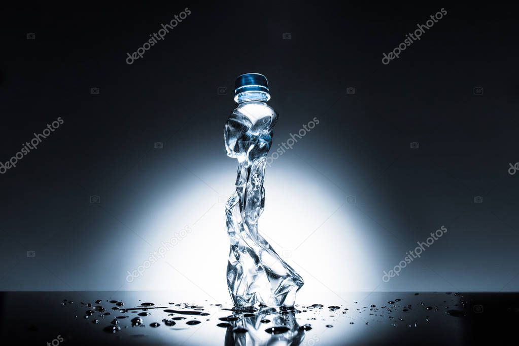 crumpled plastic bottle of water on dark 