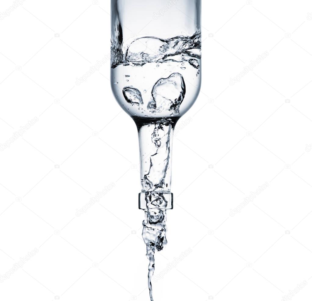 close-up shot of water pouring from glass bottle isolated on white