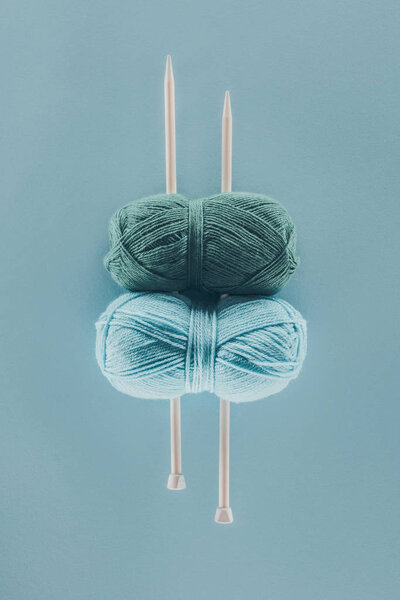 top view of blue knitting yarn with knitting needles, isolated on blue